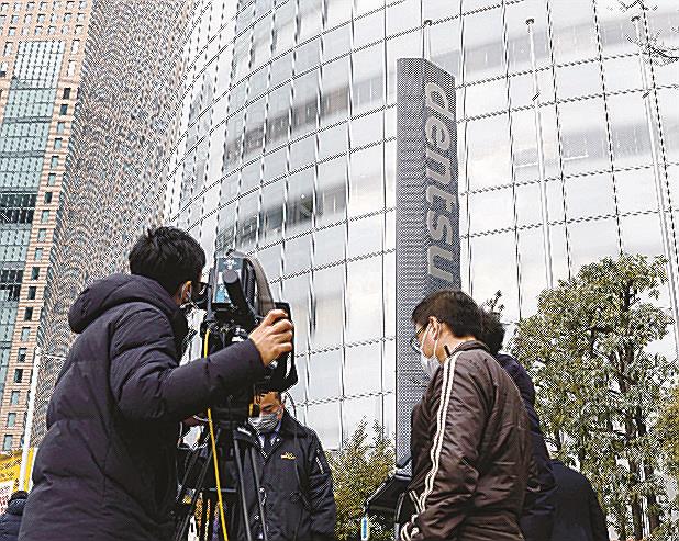電通本社が入るビル（右奥）と集まった報道陣＝８日午後、東京都港区