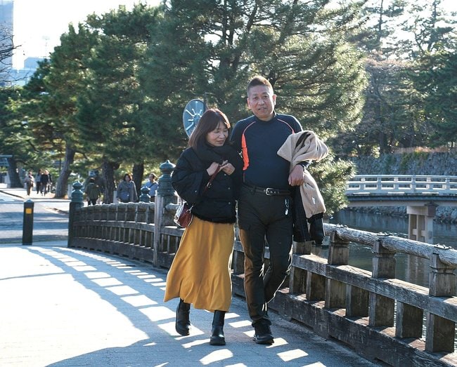 気温20度超えの暖かい陽気の中、上着を脱いで宇賀橋を歩く観光客=松江市北堀町