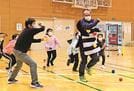 ボンチョを着た鬼（手前右）にボールを投げる「ペガーボール」で遊ぶ児童ら＝出雲市斐川町上直江、アクティーひかわ体育館