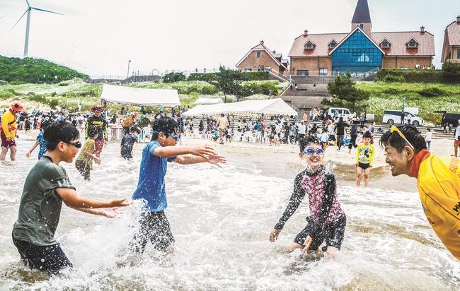 海開きで、水をかけ合う子どもたち＝出雲市多伎町多岐、キララビーチ
