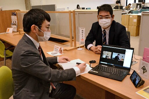 鳥取市の職員にオンライン会議のやり方を教わる記者（左）＝鳥取市幸町、市役所