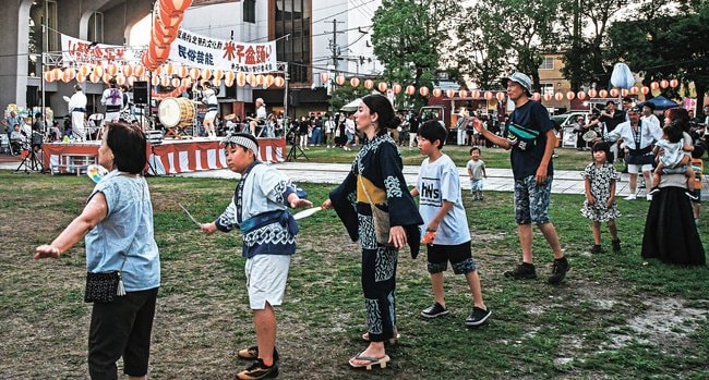 唄と太鼓に合わせて盆踊りを楽しむ来場者＝米子市角盤町２丁目、市公会堂