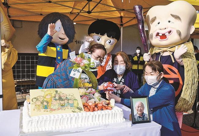ケーキに入刀する武良布枝さん（前列中央）ら＝境港市本町、水木しげる記念館の前庭