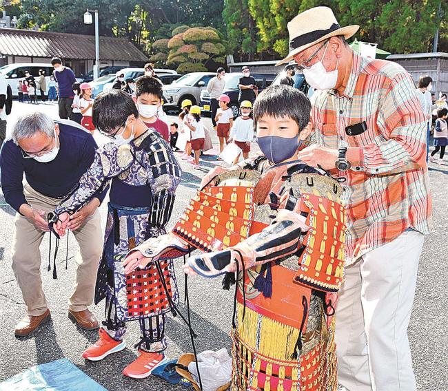厚紙製のよろいを着けてもらう子どもたち＝益田市乙吉町、雪舟の郷記念館駐車場