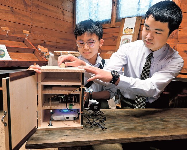 防犯機能を付けた料金箱について説明する松江高専の学生＝松江市大庭町、須山農園