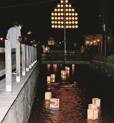 高瀬川を静かに流れる灯籠に見入る市民＝出雲市今市町
