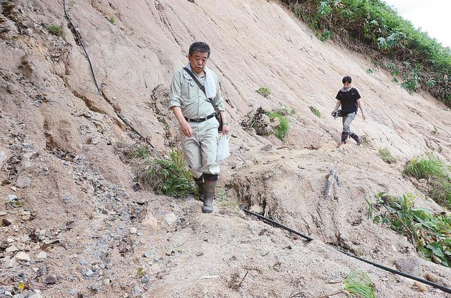 崩落前は道路だった場所を歩いて自宅との間を行き来する秦美幸さん（手前）と健治さん〓（?）雲南市三刀屋町乙加宮