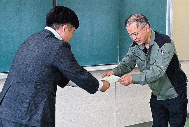 支援団体の代表に贈呈書を手渡す島根中井工業の池口順司島根工場次長（右）＝益田市須子町、市総合福祉センター