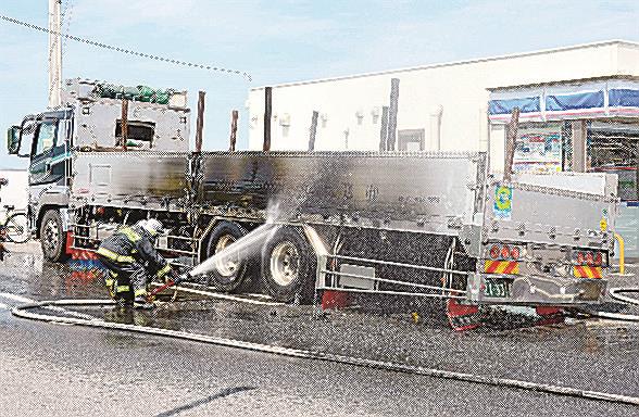 放水する消防隊員＝２１日午前１０時５分、鳥取県大山町所子、ローソン大山インター店駐車場