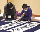 真剣な表情で筆を振るう児童（右）＝松江市殿町、松江歴史館