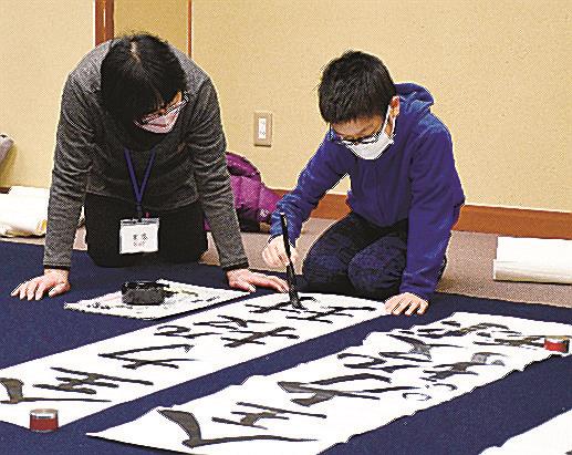 真剣な表情で筆を振るう児童（右）＝松江市殿町、松江歴史館