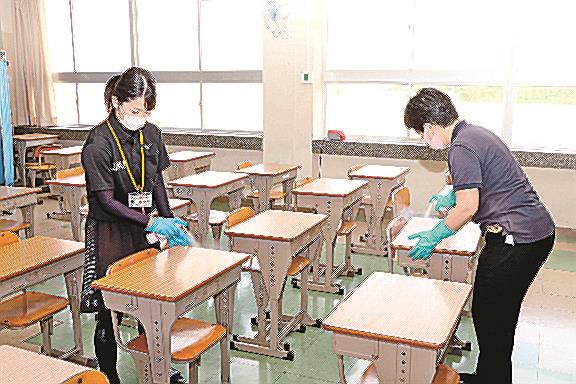「光触媒スプレー」を机に噴射する教職員=益田市津田町、東陽中学校