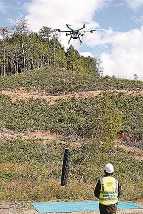 鹿よけ防護柵の支柱をつり下げ、上昇する大型運搬ドローン＝島根県美郷町上野