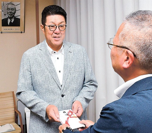 須山隆会長に寄付金を手渡す佐々岡真司さん（左）＝浜田市殿町、市役所