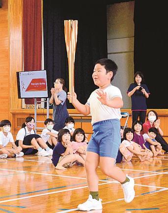 トーチを手に体育館内を走る児童＝大田市三瓶町志学、志学小学校