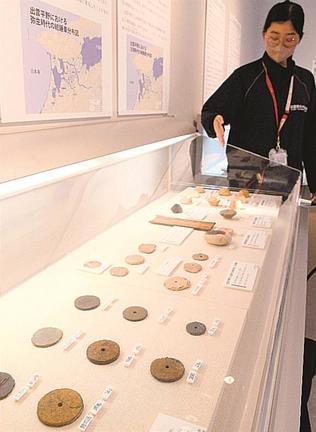 出雲市内で発掘された紡輪を紹介する永川ひかる学芸員＝出雲市大津町、出雲弥生の森博物館