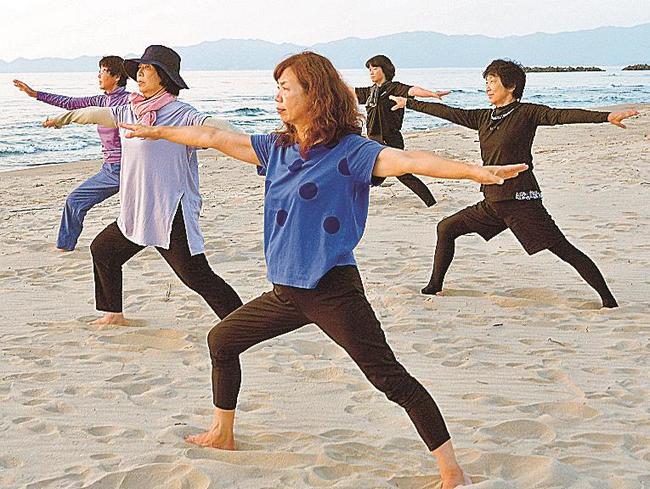 砂浜で夕日に向かってヨガを体験する参加者=出雲市多伎町久村