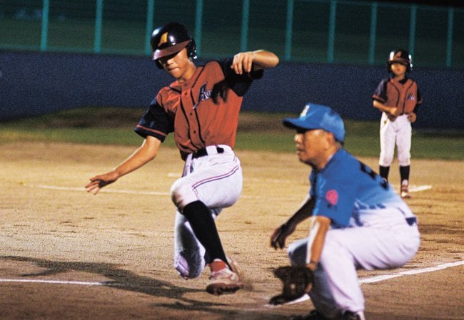 本塁に滑り込む余子スポーツ少年団の選手（左）＝境港市渡町、市営竜ケ山球場