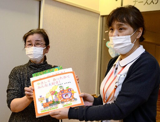 佐々木恵未さんの画集を手渡す本藤和恵管理人（左）＝出雲市姫原４丁目、島根県立中央病院