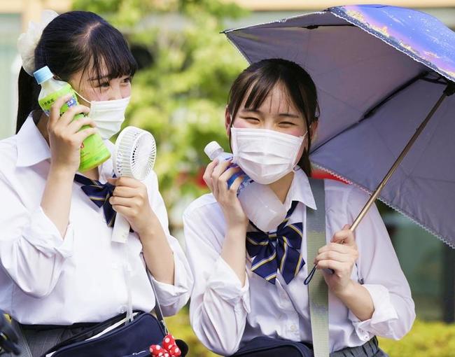 気温が４０度に到達した埼玉県熊谷市で、日傘を差して飲み物や携帯型の扇風機で涼をとる女子高生＝１日午後