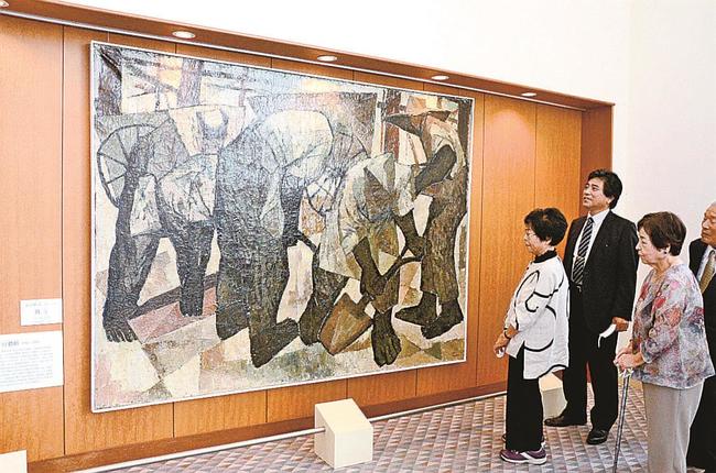 石田整昭さんの作品「働く」を眺める関係者＝米子市淀江町西原、市淀江文化センター