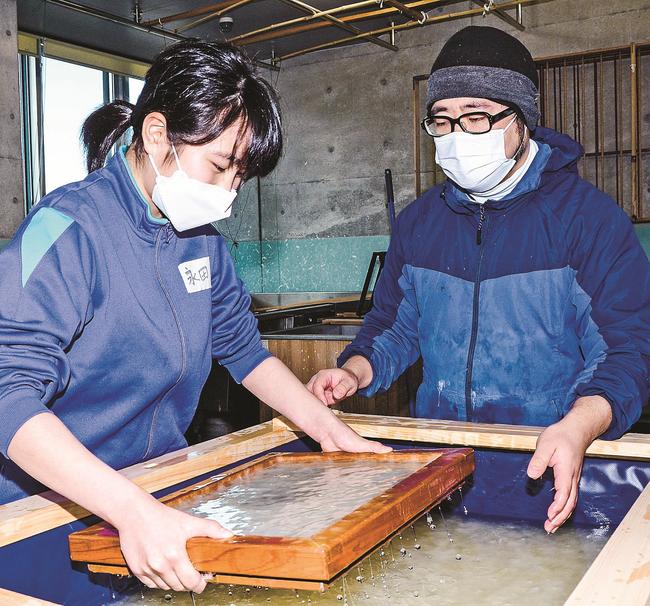 西田勝さん（右）に教わりながら卒業証書用の石州和紙をすく岡見小学校６年生＝浜田市三隅町古市場、石州和紙会館