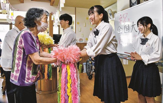 江津高校ハンドボール部員に千羽鶴を手渡すデイサービス利用者＝江津市和木町、よろこぼう屋