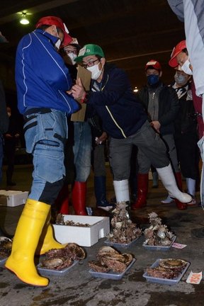 「懐競り」で入札する仲買人（左）＝浜田市原井町、浜田漁港