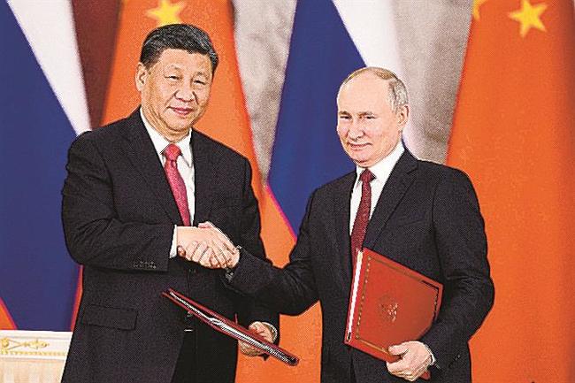 モスクワのクレムリンで共同声明に署名後に握手するロシアのプーチン大統領（右）と中国の習近平国家主席＝２１日（タス＝共同）