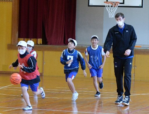 ニック・ケイ選手（右）とバスケットボールを楽しむ児童＝松江市古曽志町、古江小学校