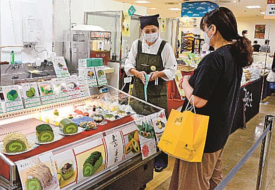 抹茶のロールケーキを買い求める来店客(右)=米子市角盤町1丁目、JU米子高島屋