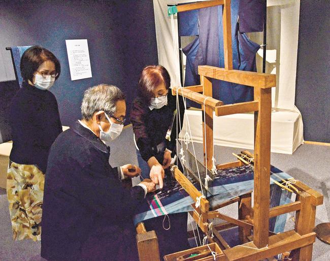 遠藤京子さん（右）の手ほどきを受け、機織りを体験する来場者＝安来市広瀬町布部、加納美術館
