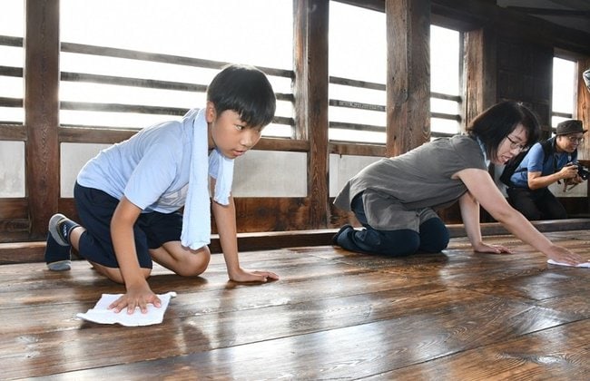 雑巾で松江城の床を磨く家族連れ＝松江市殿町