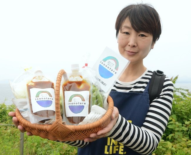 伊野地区の住民で手がけ、販売を開始した焼き肉のたれを持つ朝枝尚子さん=出雲市美野町、よっ得!?伊野いち