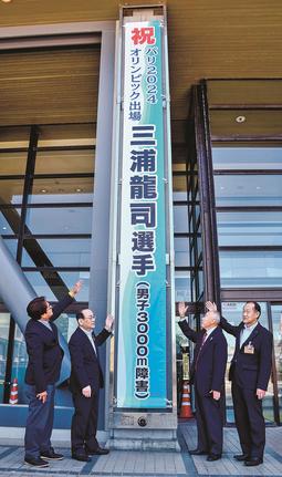 三浦龍司選手の五輪出場を祝う懸垂幕を披露する関係者＝浜田市殿町、市役所