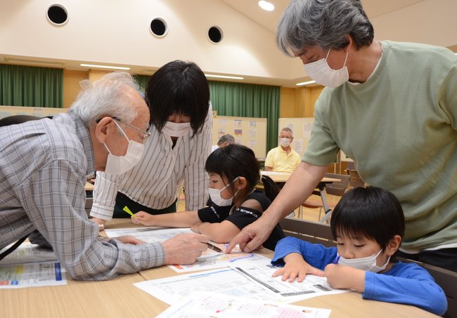 市のハザードマップを見ながら、川や自宅の位置を確認する親子連れたち＝出雲市松寄下町、高松コミュニティセンター
