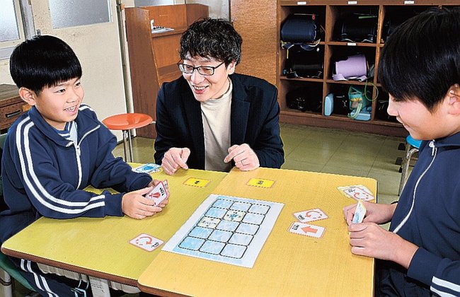 講師の工藤良さん(中央)に教わり、ボードゲームを楽しむ児童=益田市戸田町、戸田小学校