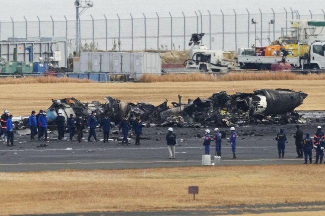 焼け焦げた海上保安庁の航空機の周辺に集まる警視庁の捜査員や東京消防庁の隊員ら＝３日午前１１時１２分、羽田空港