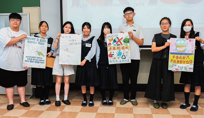 生徒からポスターを受け取る中国と韓国の学生たち=出雲市下古志町、出雲西高校
