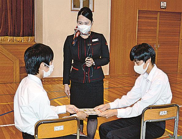 生徒に物の受け渡しのマナーを指導する客室乗務員の相沢萌子さん＝出雲市神門町、河南中