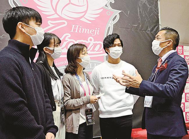 橋本明社長(右端)から板倉さんの奮闘ぶりを聞く妻の千夏さん(左から3人目)ら家族=兵庫県姫路市、ヴィクトリーナ・ウインク体育館