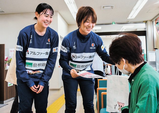 来店客にチラシを配る秋田咲良さん（左）と尾添有紗さん＝出雲市姫原１丁目、島根銀行出雲支店
