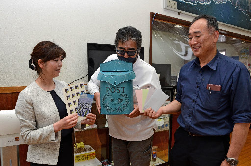 投函された手紙を手に喜ぶ「知夫あおぞら郵便局」のメンバー=島根県知夫村、ホテル知夫の里