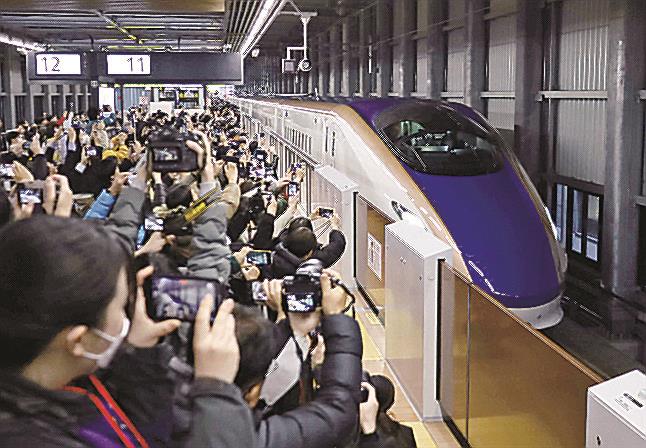 北陸新幹線の金沢―敦賀間が延伸開業し、ＪＲ福井駅に到着した東京行きの一番列車「かがやき５０２号」を出迎える大勢の人たち＝１６日午前、福井市
