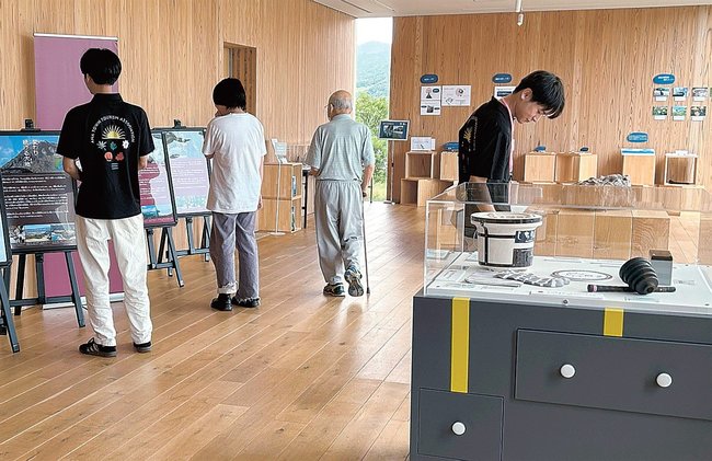 日用品に使われる鉱物の展示を見る来場者（右）＝島根県海士町福井、Ｅｎｔôジオラウンジ