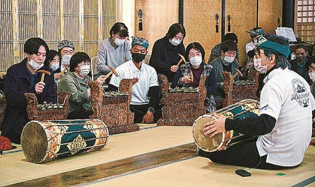 梅田英春教授（右）に教わりながら、ガムランの楽器演奏を体験する参加者＝島根県美郷町粕渕、浄土寺