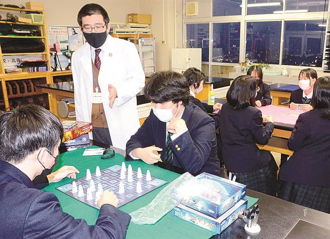 卓を囲んでゲームを楽しむ同好会のメンバーと田中薫教諭（左から２人目）〓（?）松江市西津田９丁目、開星中学・高校