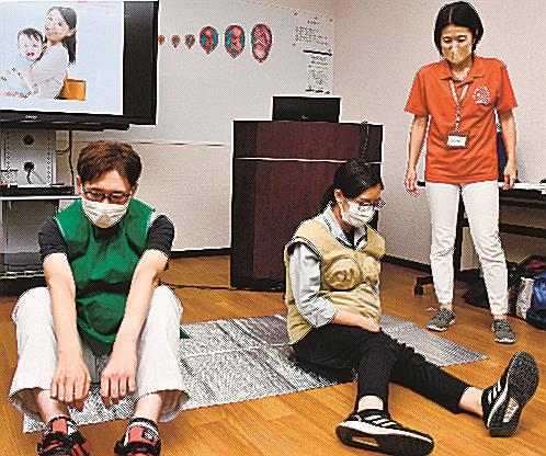 妊婦の体を模したジャケットを着て、不便さを体感する社員＝松江市東出雲町揖屋、樋野電機工業
