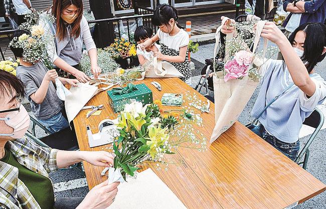 好みの花を切りそろえて袋に入れ、花束を作る参加者＝鳥取市弥生町、若桜街道