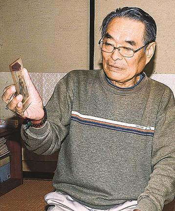 松本京子さんの写真を眺める孟さん＝米子市内和田町